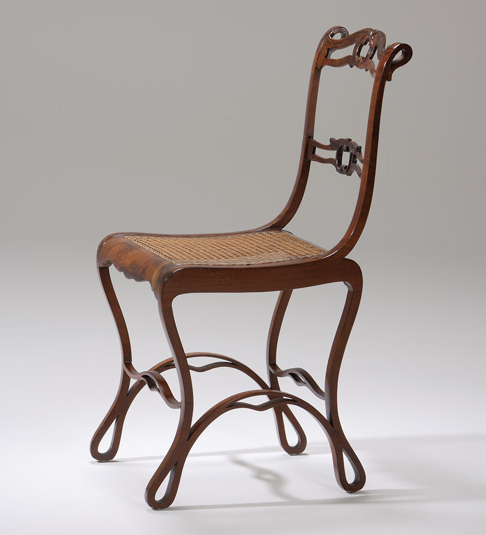 A curvy chair with thin legs and back. The seat is made of a basket-weave styled piece of wood. 